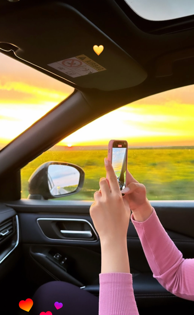 Taking a photo of a beautiful sunset from the car passenger seat